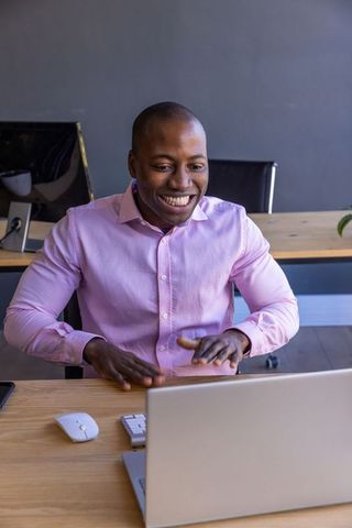 Businessman in Pink Shirt Smiling During Video Call