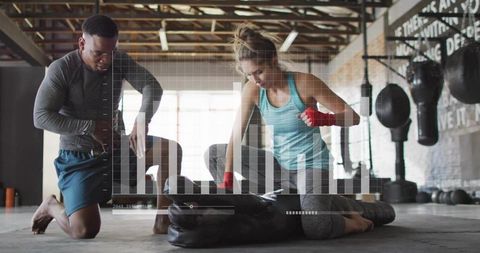 Female boxer training with coach in brick gym wearing turquoise top and red hand wraps