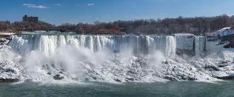 Panoramic niagara falls winter cascade with icy rocks, rushing mist and frozen edges