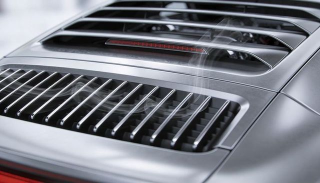 Showcasing silver sports car engine decklid with chrome louvers, recessed brake light, vapor