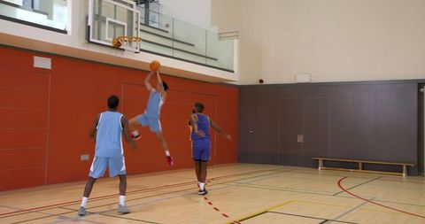 Athletes Engaged in Competitive Basketball Game in Indoor Court