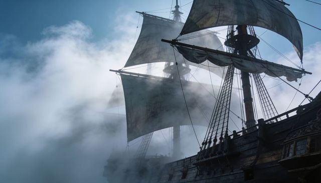 Tall ship emerging from fog, sailing with billowing square sails and rigging