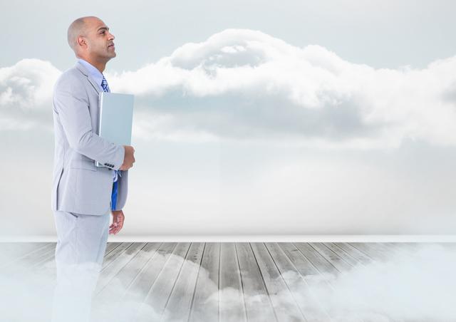 Businessman wearing gray suit holding laptop while standing on wooden pier amidst clouds. This creates a surreal and futuristic visual suggesting aspiration, ambition, or visionary thinking. Suitable for corporate marketing, business concepts, future vision, motivational, and mission statements.