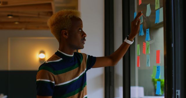 Focused Professional Organizing Sticky Notes on Glass Wall in Office - Download Free Stock Images Pikwizard.com