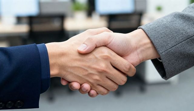 Corporate handshake close-up showing agreement between colleagues in navy and gray suits