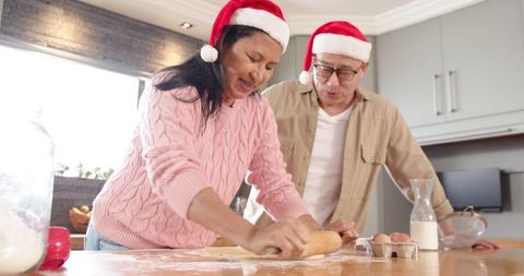 Cheerful Couple Preparing Holiday Cookies in Santa Hats