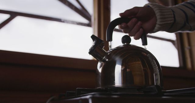 Hand Holding Kettle Ready for Boiling Water in Cozy Kitchen - Download Free Stock Images Pikwizard.com