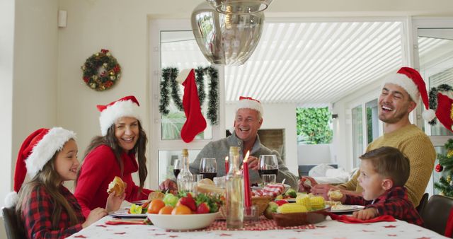 Family cheerfully enjoying Christmas meal wearing Santa hats, sitting around decorated table filled with food, holiday decorations visible, demonstrating holiday joy and family bonding. Ideal for holiday cards, festive advertisements, or promoting family-oriented products and services.