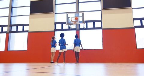 Teenage Girls Practicing Basketball in Gymnasium
