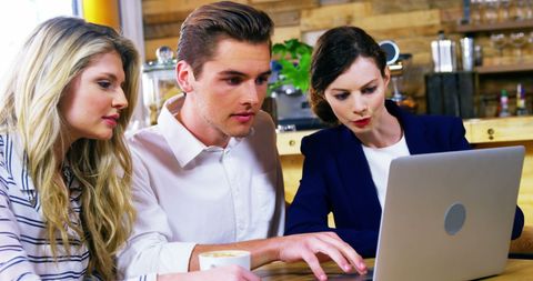 Friends Collaborating on Laptop in Cozy Cafe Environment