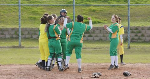 Team celebration on softball field in vibrant green uniforms