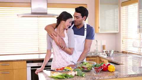 Happy Couple Embracing While Cooking in Bright Kitchen
