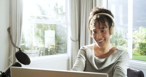 African american woman recording podcast from minimalist home workspace with headphones