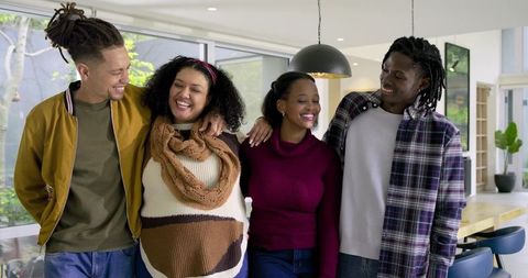 Diverse friends laughing together in modern kitchen, cozy knit scarf, daylight warmth