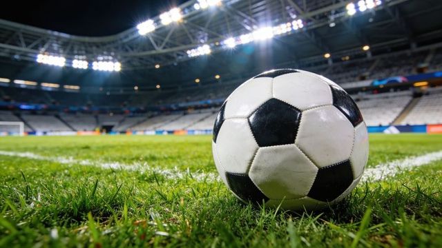Classic black and white soccer ball resting on stadium turf under floodlights