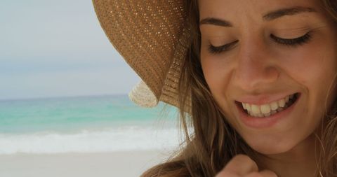 Smiling Woman Wearing Beach Hat by Ocean Shoreline