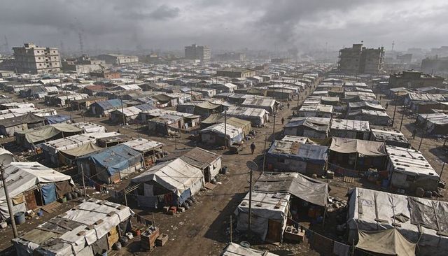 Tarpaulin shelters lining urban outskirts in grid of makeshift tents