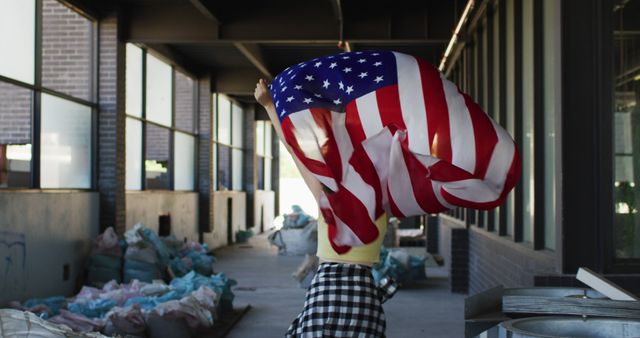 Person waving American flag near industrial warehouse entrance - Download Free Stock Images Pikwizard.com