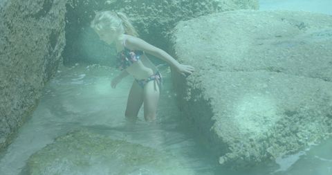 Child Exploring Rocky Seaside in Playful Swimwear on Vacation
