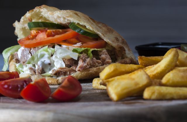 Tuna sandwich filled with fresh vegetables such as tomatoes, lettuce, and cucumbers, served with crispy potato fries. This image is ideal for food blogs, restaurant menus, food advertisements, or any health and nutrition-related content.