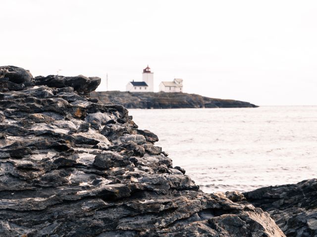 Lighthouse perched on rocky coastline overlooking ocean, providing guidance in coastal navigation. Serene autumn atmosphere with soft light creates tranquil mood. Great for themes related to travel, navigation, nature, place of interest, serenity, maritime history.