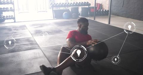 Performing seated medicine ball rotations building core strength in industrial gym