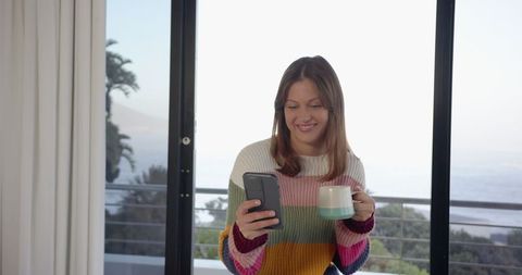 Woman Leisurely Drinking Coffee on Coastal Balcony
