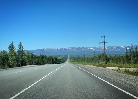 Endless Open Road with Distant Mountains and Clear Blue Sky