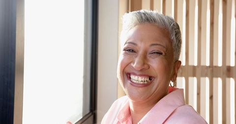 Joyful Mature Woman by Window Embracing Natural Light
