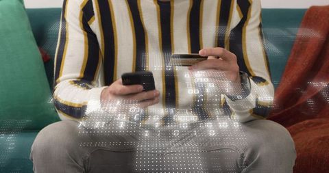Man holding phone and credit card making mobile payment with binary data overlay