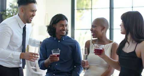 Friends celebrating with red wine and champagne flutes in modern living room casual gathering