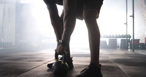 Determined Athlete Lifting Kettlebell in Warehouse Gym