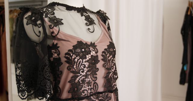 Close up of a black lace dress with pink underlay displayed on a mannequin in a fashion boutique, slow motion