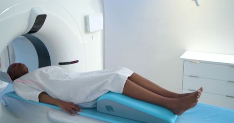 Female patient undergoing ct scan lying on padded table in clean hospital imaging room