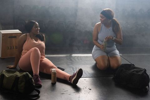 African american friends resting, hydrating and talking after strength training