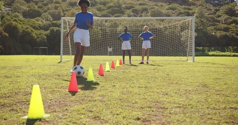 Girls Practicing Soccer Dribbling on Sunny School Field