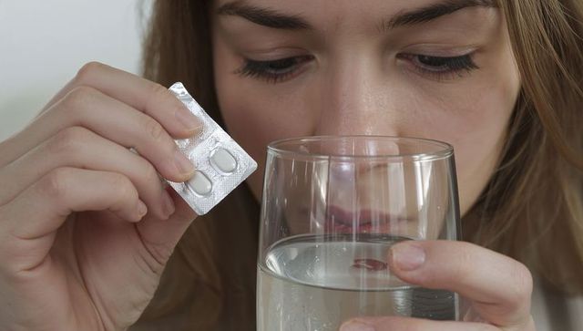 Young woman taking tablets with water closeup for medication, wellness, selfcare