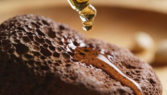 Golden syrup dripping onto aerated chocolate cake close-up with glass dropper macro