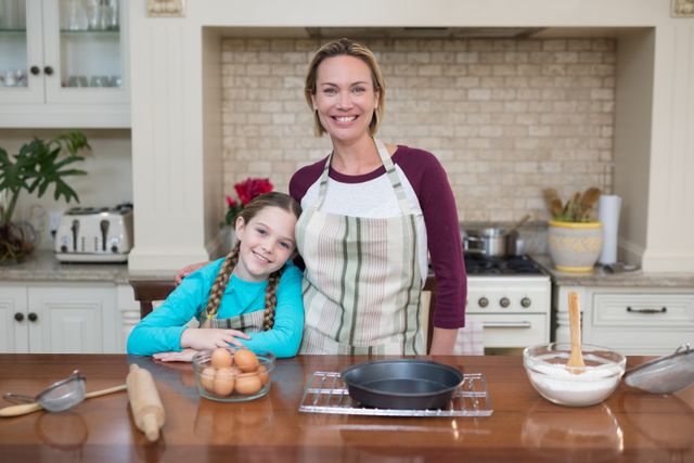 Portrait of smiling mother and daughter standing in the kitchen