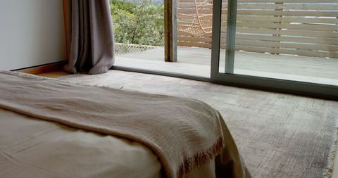 Minimalist bedroom view with cozy outdoor deck and wicker chair