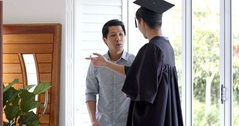 Proud Father Supporting Graduating Son at Home Celebration