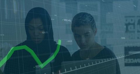 Two women studying laptop with green financial analytics chart overlay in modern office