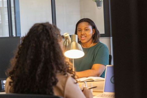 Black businesswoman leading collaborative meeting with colleague at modern office desk