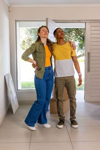 Young diverse couple inspecting new home entryway during first walkthrough with boxes