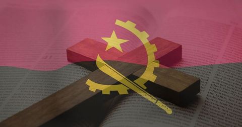 Wooden cross casting shadow over open book with angola flag overlaying, faith and national symbolism