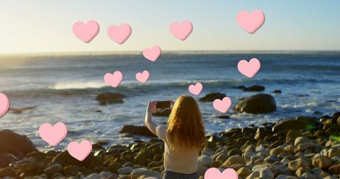 Woman Taking Photos on Rocky Beach with Digital Heart Overlays