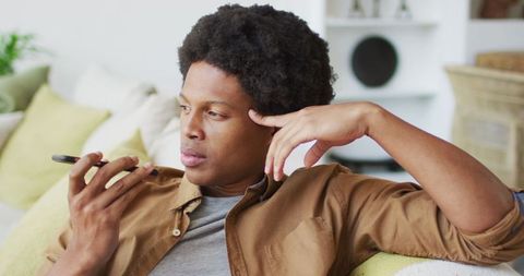 African american man relaxing at home using smartphone