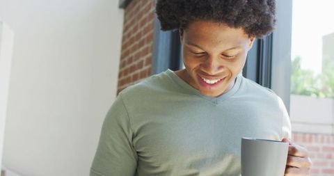 Man Enjoying Coffee and Smartphone Indoors, Natural Light