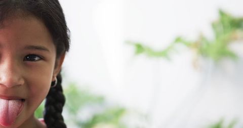 Joyful Child Playfully Sticking Out Tongue With Green Festive Background