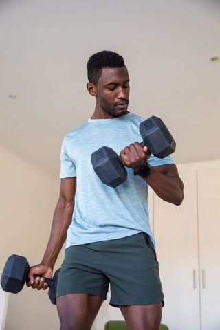 Focused African American Man Lifting Dumbbells in Home Gym